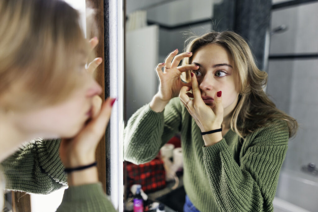 teenage girl putting in contact lenses