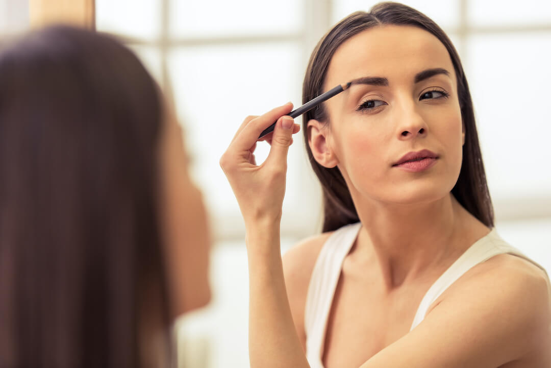 woman applying makeup to her eyebrows
